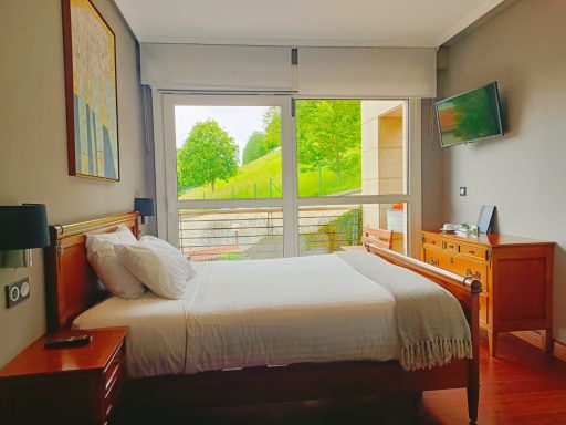 Habitación luminosa con cama doble, ventana grande y vistas al jardín. Mobiliario elegante.