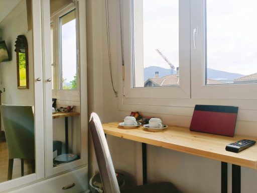 Escritorio con dos tazas, un teléfono y una ventana que muestra un paisaje montañoso.