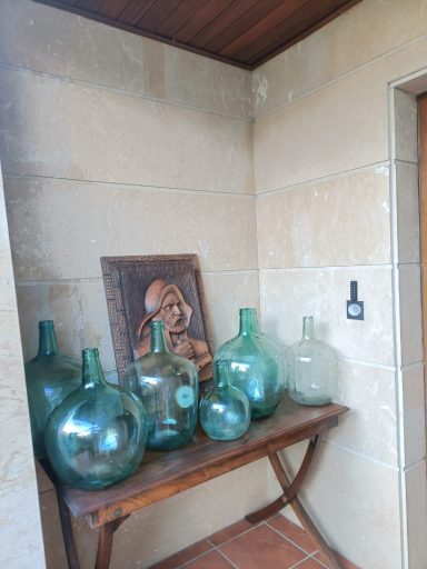 Botellas de vidrio verde dispuestas en una mesa de madera en una esquina decorativa.