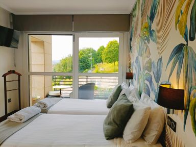 Detalle de vistas habitación 102 Habitación con dos camas, decoración floral y vistas al exterior.