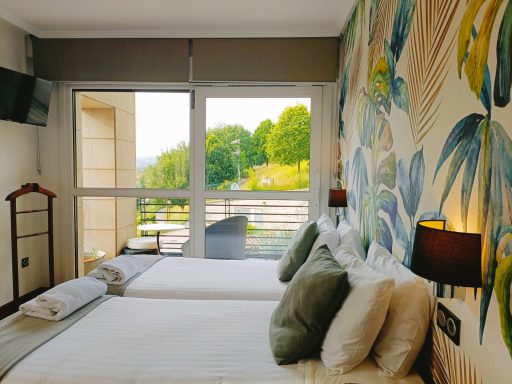 Habitación con dos camas, decoración floral y vistas al exterior.
